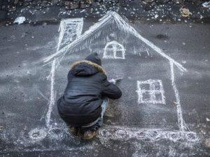 Enfant qui dessine une maison à la craie